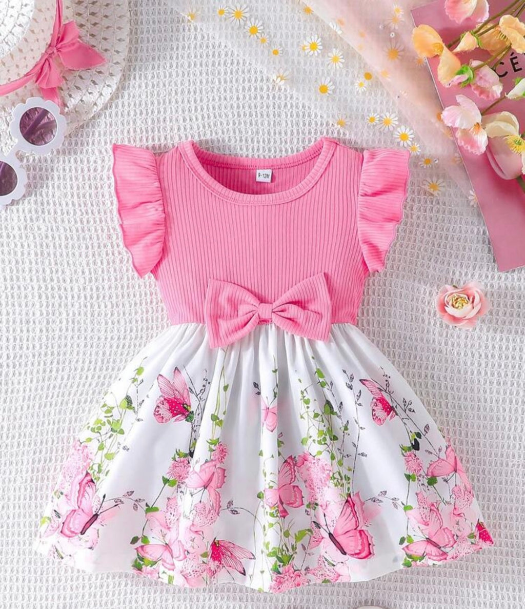 Pink top with ruffled sleeves and floral skirt on a textured surface with decorative elements.