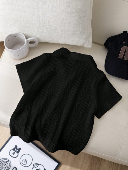 Black sweater on a white couch with a mug and hat in the background