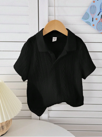 Black short-sleeve shirt on a wooden hanger against a white wooden panel background