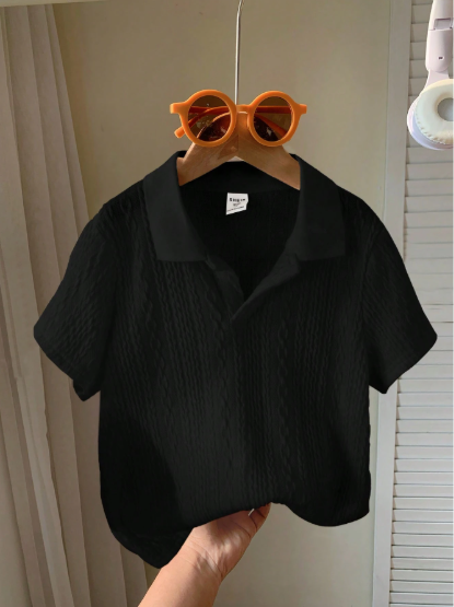 Black shirt on a hanger with orange sunglasses above it against a neutral background